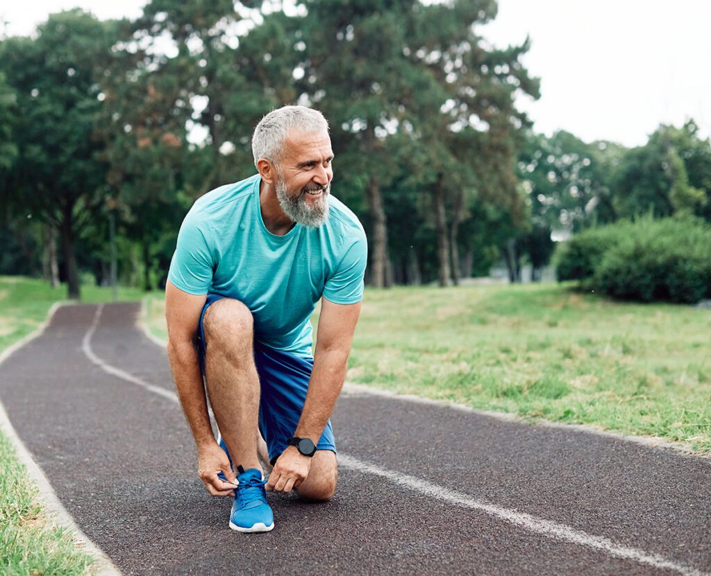 Portrait of a happy active mature or middle aged senior man posing fixing shoelace.