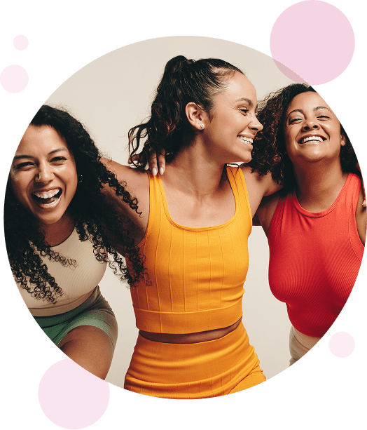 Three women laughing and smiling while holding arms.