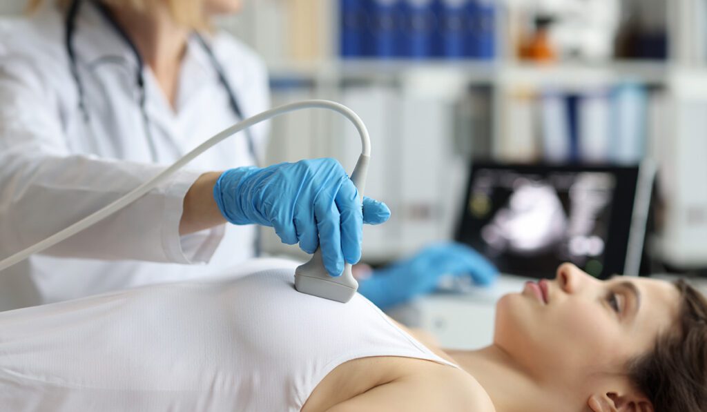 Doctor performing breast ultrasound on women.