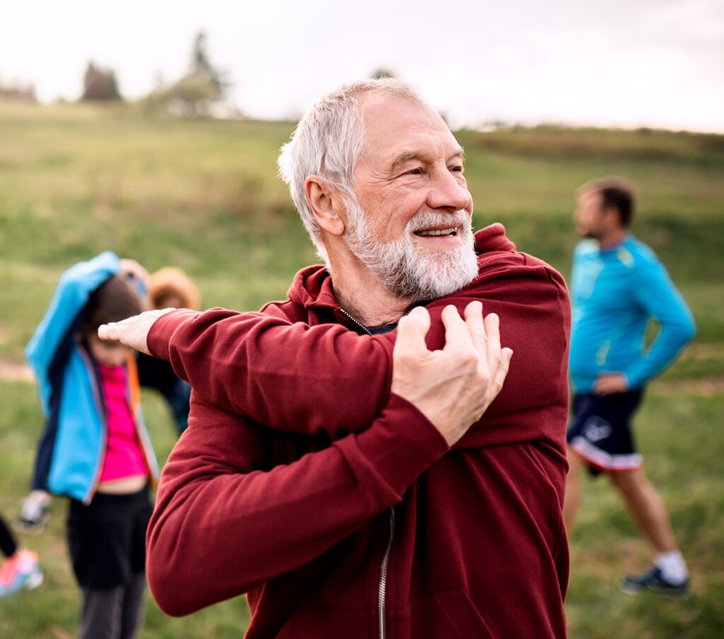Older man stretching and doing yoga outside.