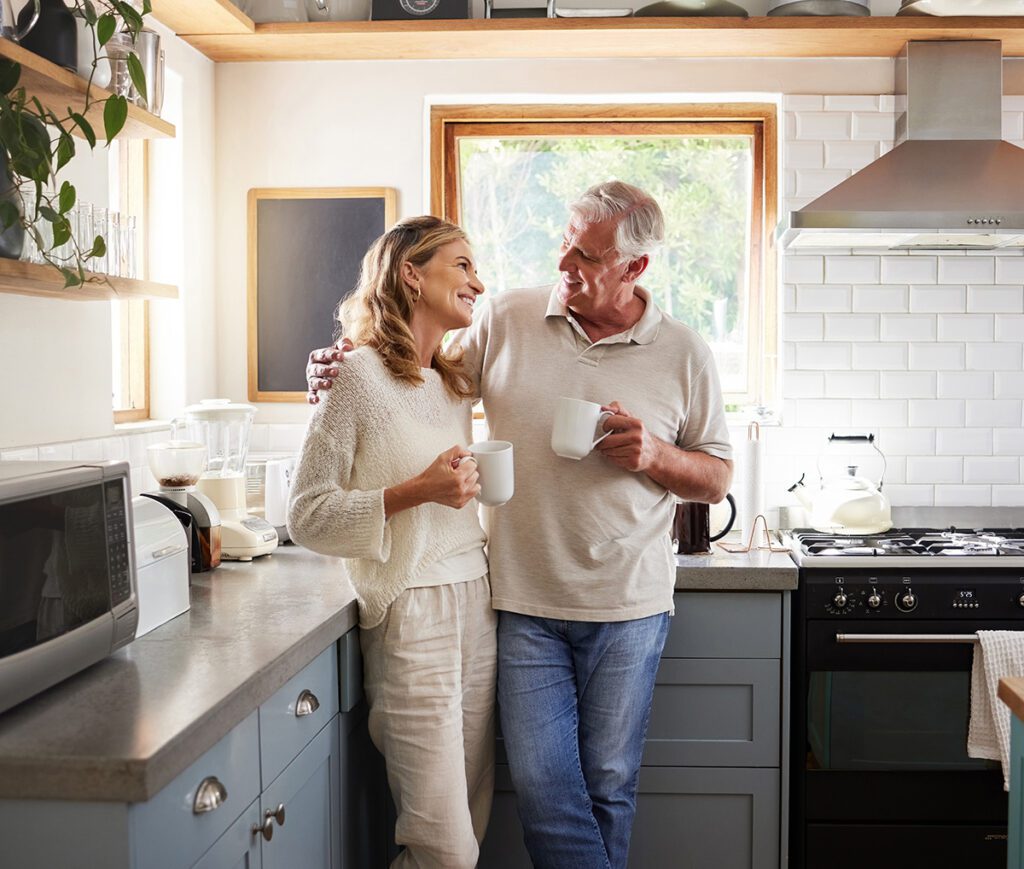 Happy older couple smiling at each other having some coffer.