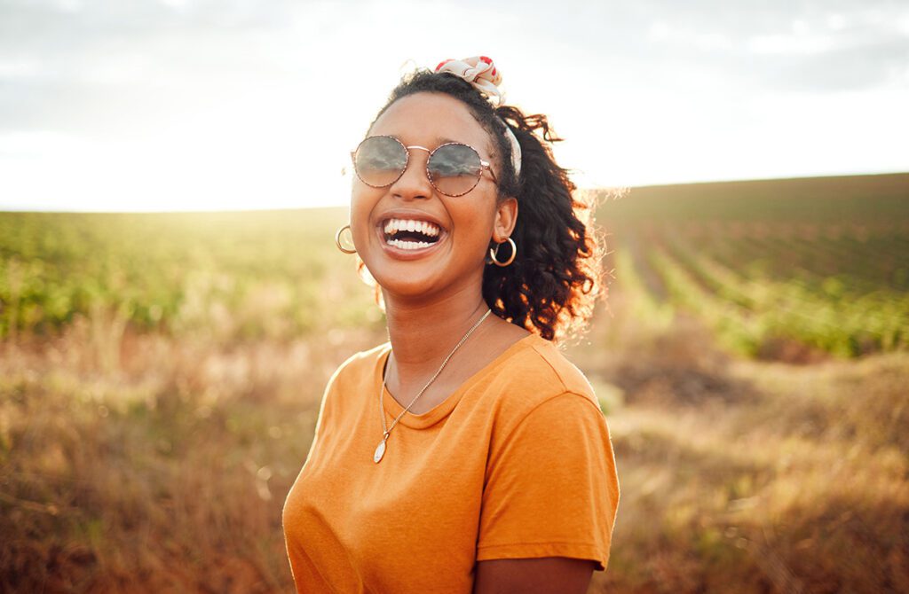 Happy women on farm smiling with sun in background.