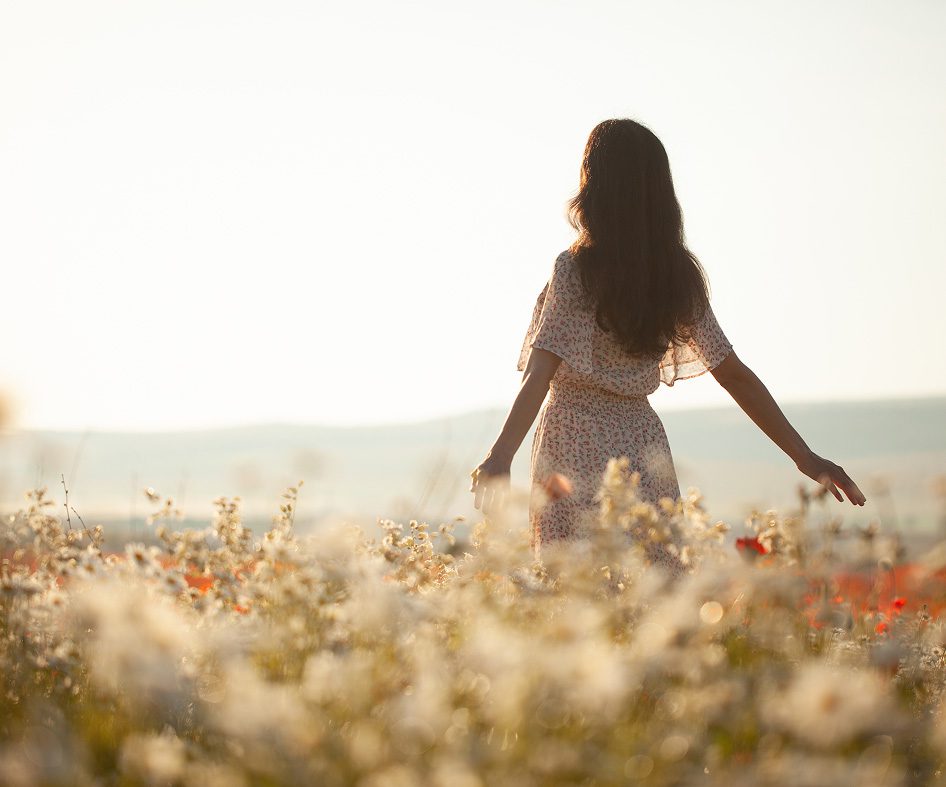 Women walking free in wheat fields with sun shining in the background.