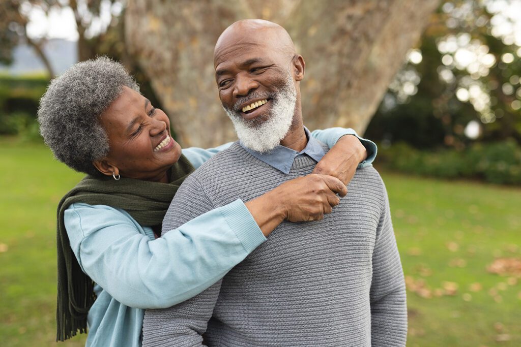 happy elderly couple smiling and hugging outside in a park