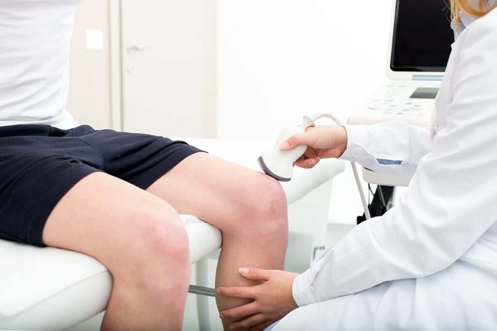 Ultrasound on knee patient in doctors room.