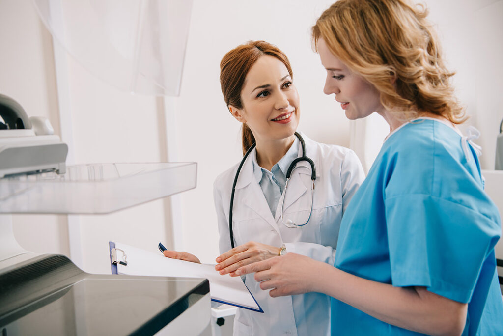 smiling radiologist holding clipboard while standing near patient